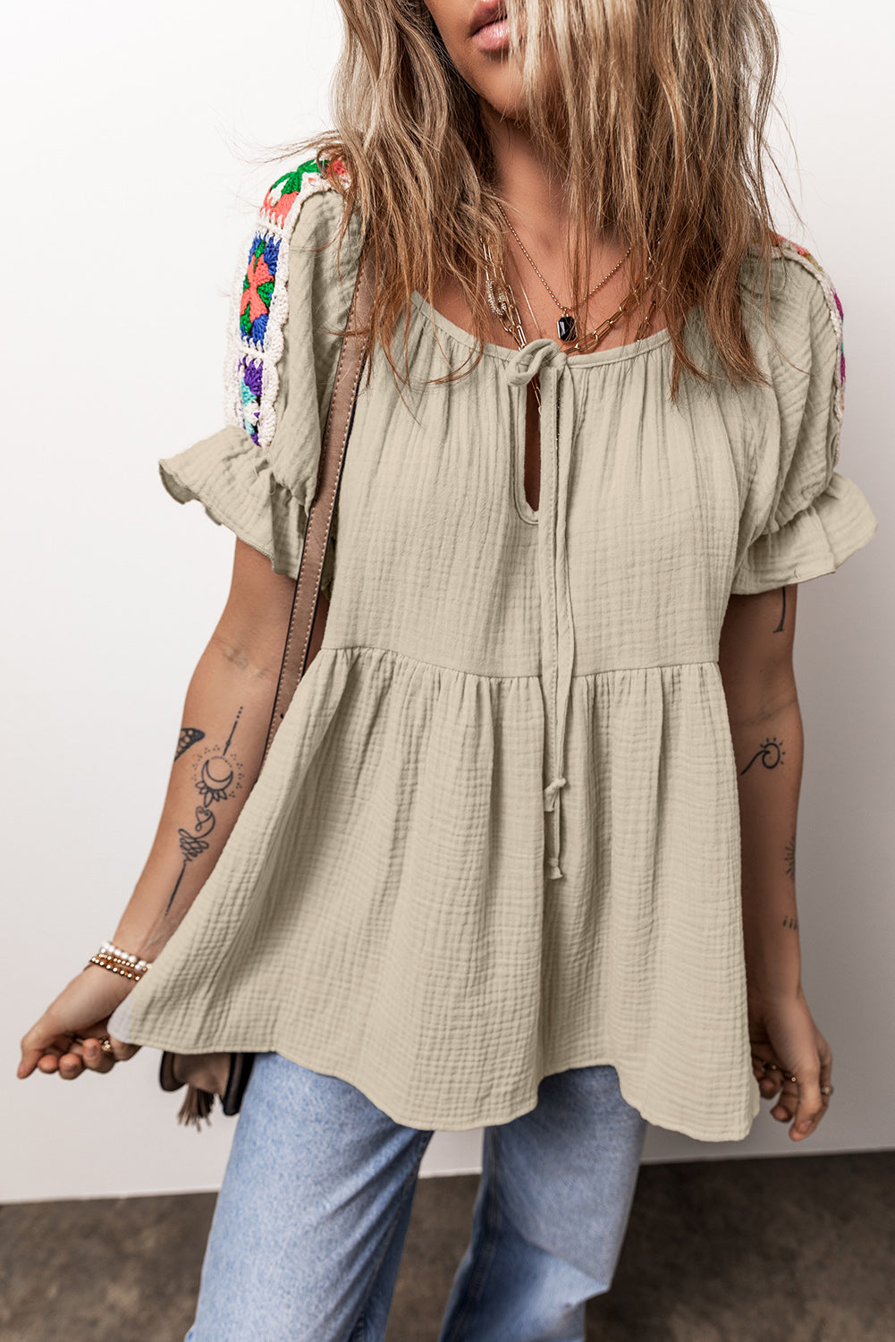 Rookgrijze, gekreukelde, geborduurde blouse met bellenmouwen en gestrikte hals
