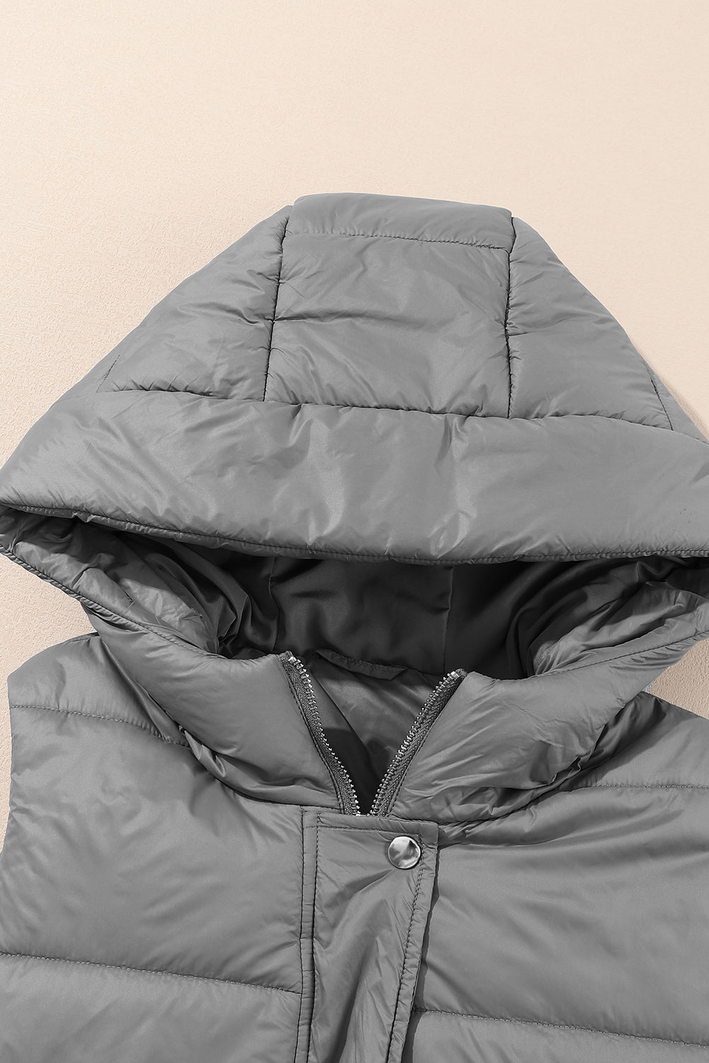 Donkergrijze lange gewatteerde vestjas met capuchon