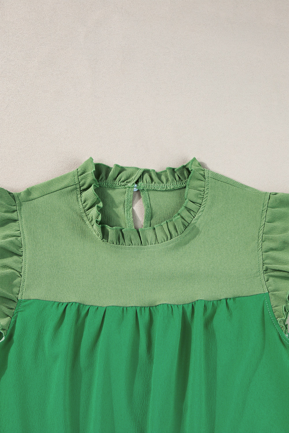 Heldergroene tweekleurige blouse met ruches en fladdermouwen